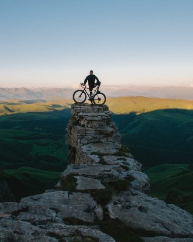 man holding bike while standing on gray mountain