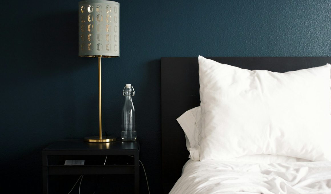 gray table lamp beside white bed pillow