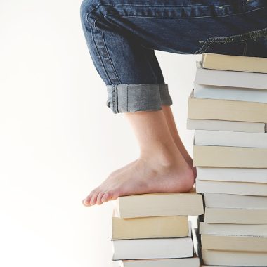 person sitting on stack of books while reading