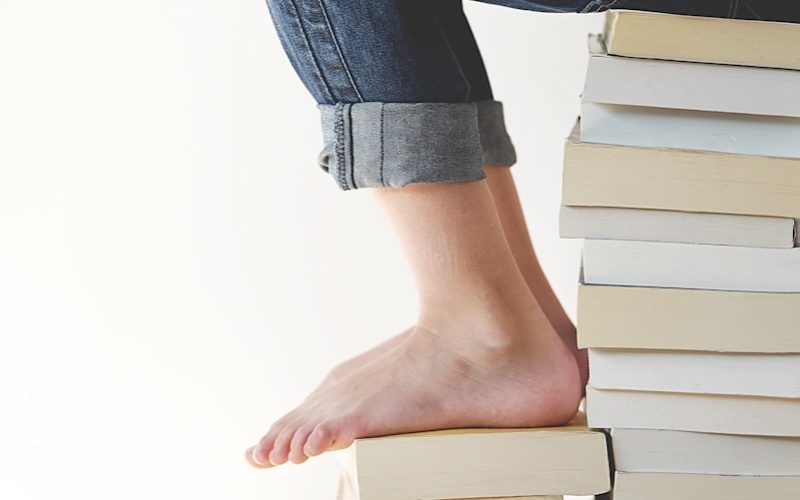 person sitting on stack of books while reading