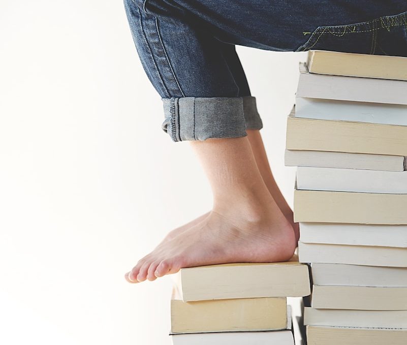 person sitting on stack of books while reading